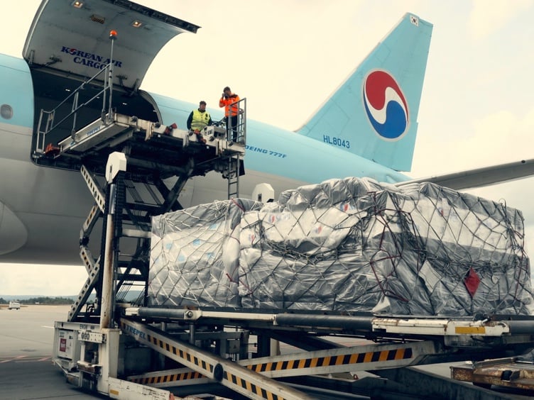 Lasteoperasjon av cargo på Korean Air Boeing 777F på en flyplass, med arbeidere og sikret frakt på en heis