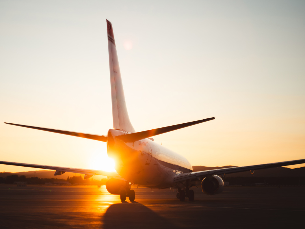 Commercial airplane on runway during sunrise, highlighting silhouette and golden sky