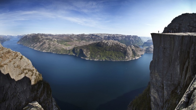 Utsikt fra klippekanten av Preikestolen over Lysefjorden i Norge, med blå himmel og steinete landskap