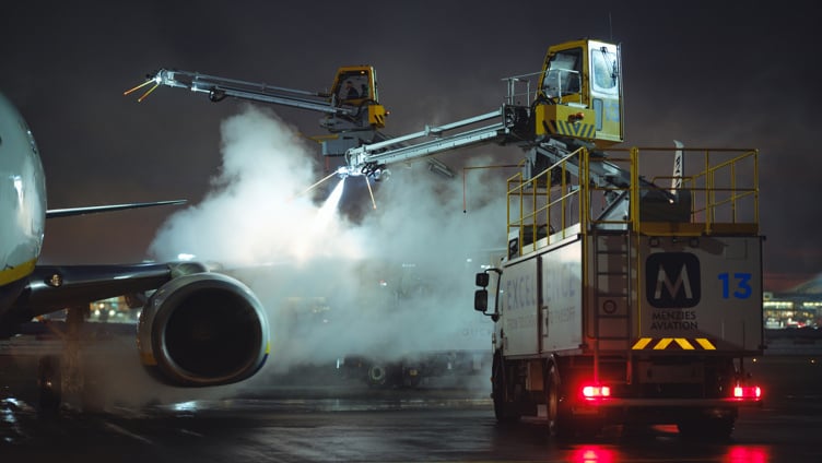 Fly som avises om natten på en flyplass tarmac, ved bruk av spesialiserte kjøretøy og utstyr for å sikre trygge flyoperasjoner