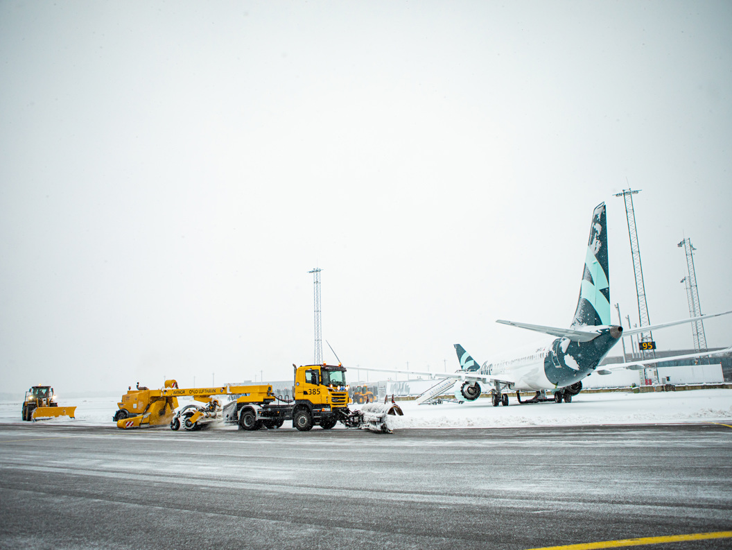 Fly på snødekket rullebane med brøytebiler på Oslo Lufthavn under vinterforhold